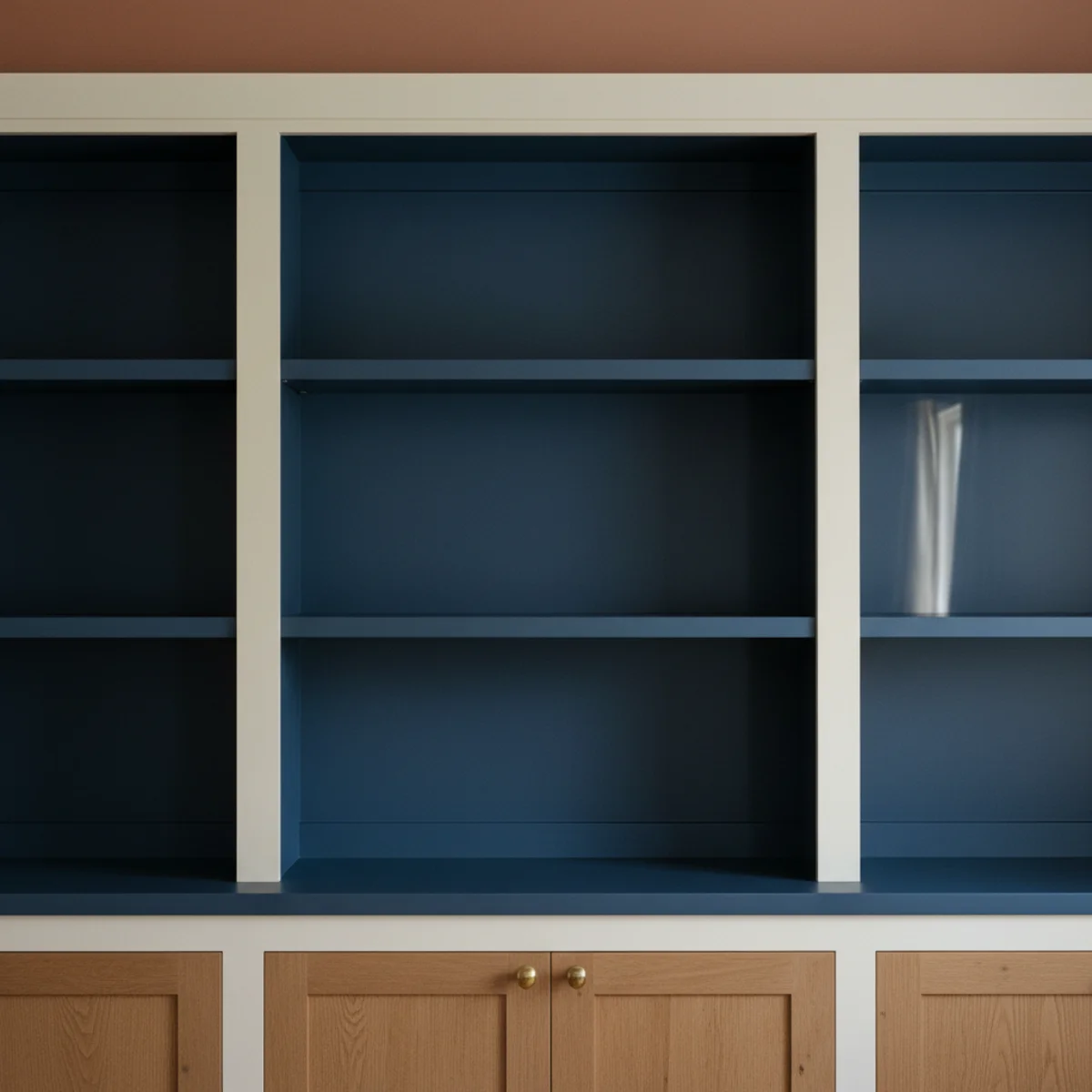 Navy decor warm — navy-painted built-in bookcase with cream trim and aged brass lamp beside it in a warm living room showing contained architectural navy application — Home Decor Aura